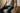 man sitting on a medium firm footstool cushion, but don't show the face, focus on the seating and posture, zoom in on the figure touching the cushion